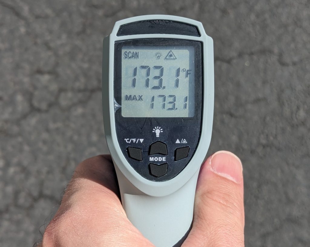 Thermometer measuring pavement in direct sun at 173°F